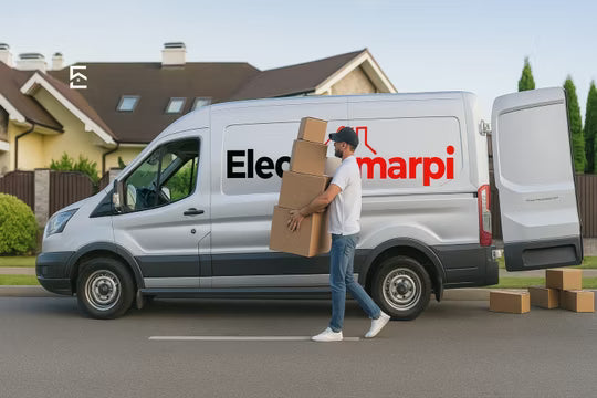 A white delivery van with the Electromarpi logo is parked on a residential street with a man carrying cardboard boxes beside it.